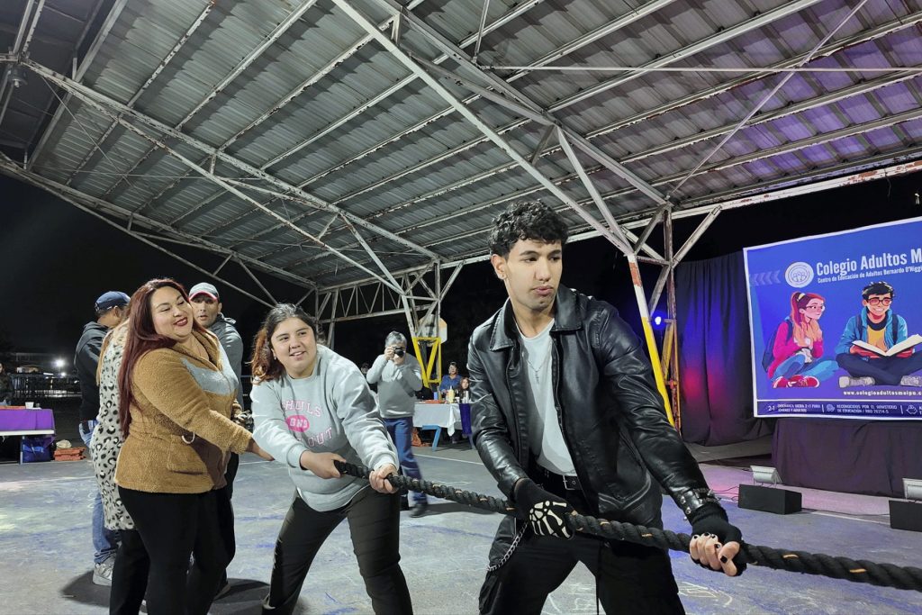 Estudiantes compitiendo en el juego de tirar la cuerda en el patio techado