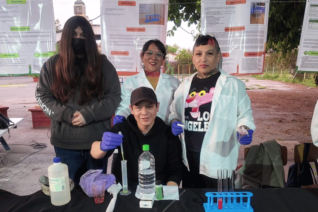 Estudiantes con delantal y guantes haciendo un experimento de química en la Feria de Ciencias