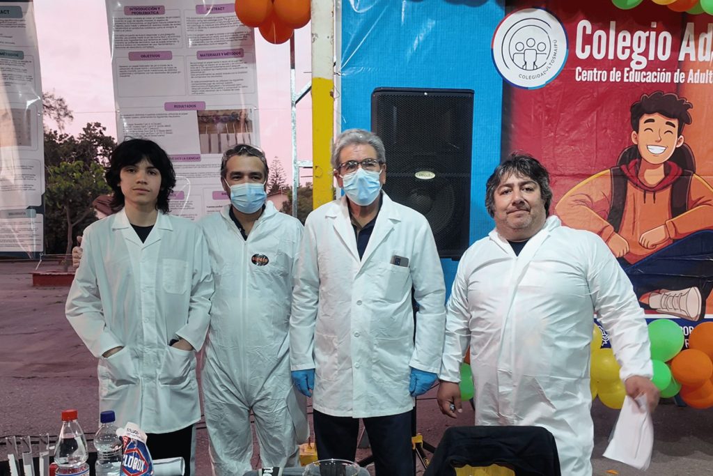 Estudiantes con delantal y mascarilla en su stand de la Feria de Ciencias