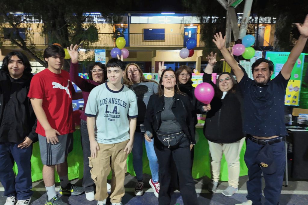 Estudiantes celebrando con globos en su stand de la feria