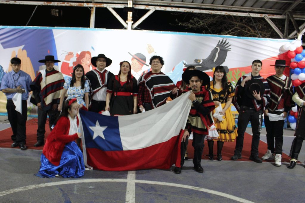 Estudiantes con ponchos sosteniendo la bandera chilena en la Fiesta de la Chilenidad