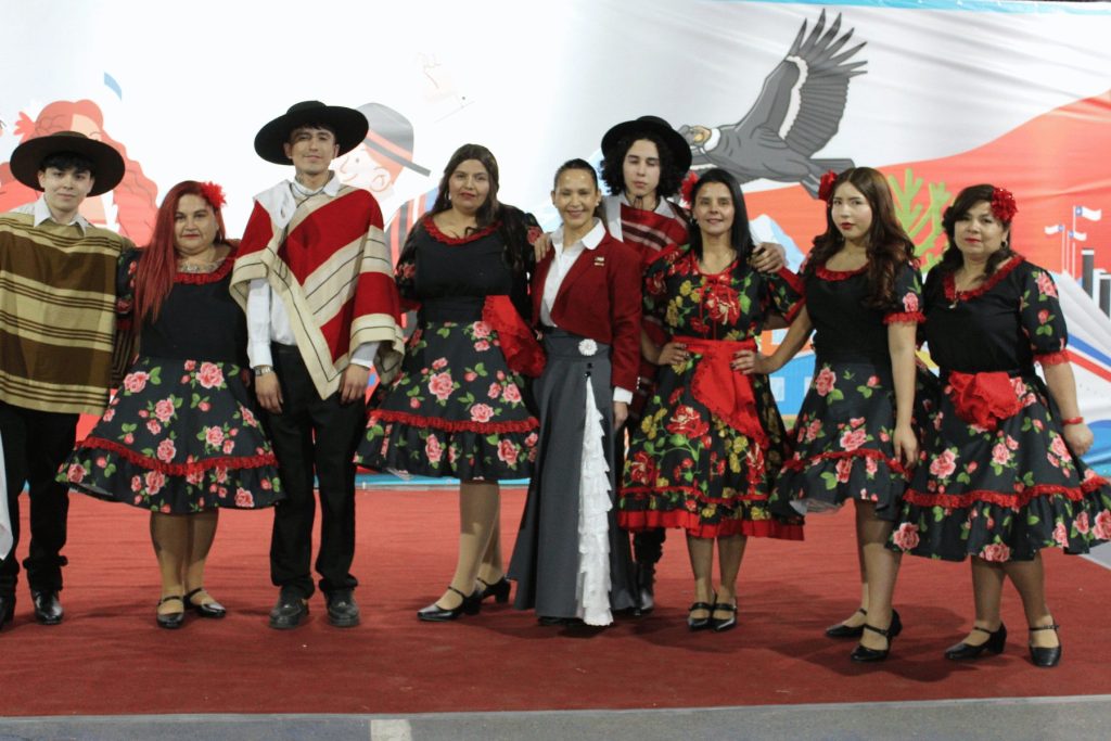 Grupo de baile de cueca con vestidos floreados en la Fiesta de la Chilenidad